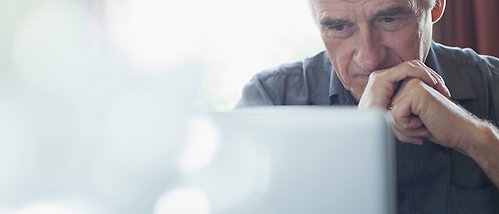 äldre man sitter vid dator